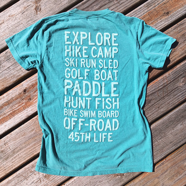 Sea Foam Blue 45th Parallel Puff Ink Activity Tee with adventure-themed text on the back, perfect for outdoor activities.