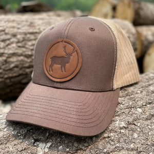 Brown 45th Parallel Elk Leather Patch Snapback Trucker Hat on log background