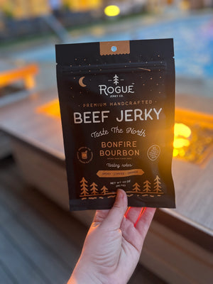 Rogue Jerky in Bonfire Bourbon held near campfire