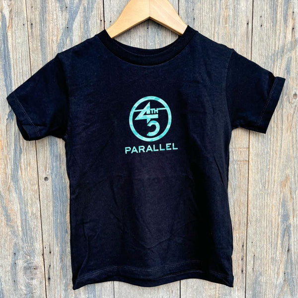 Black toddler camo logo tee with teal design on wooden hanger.